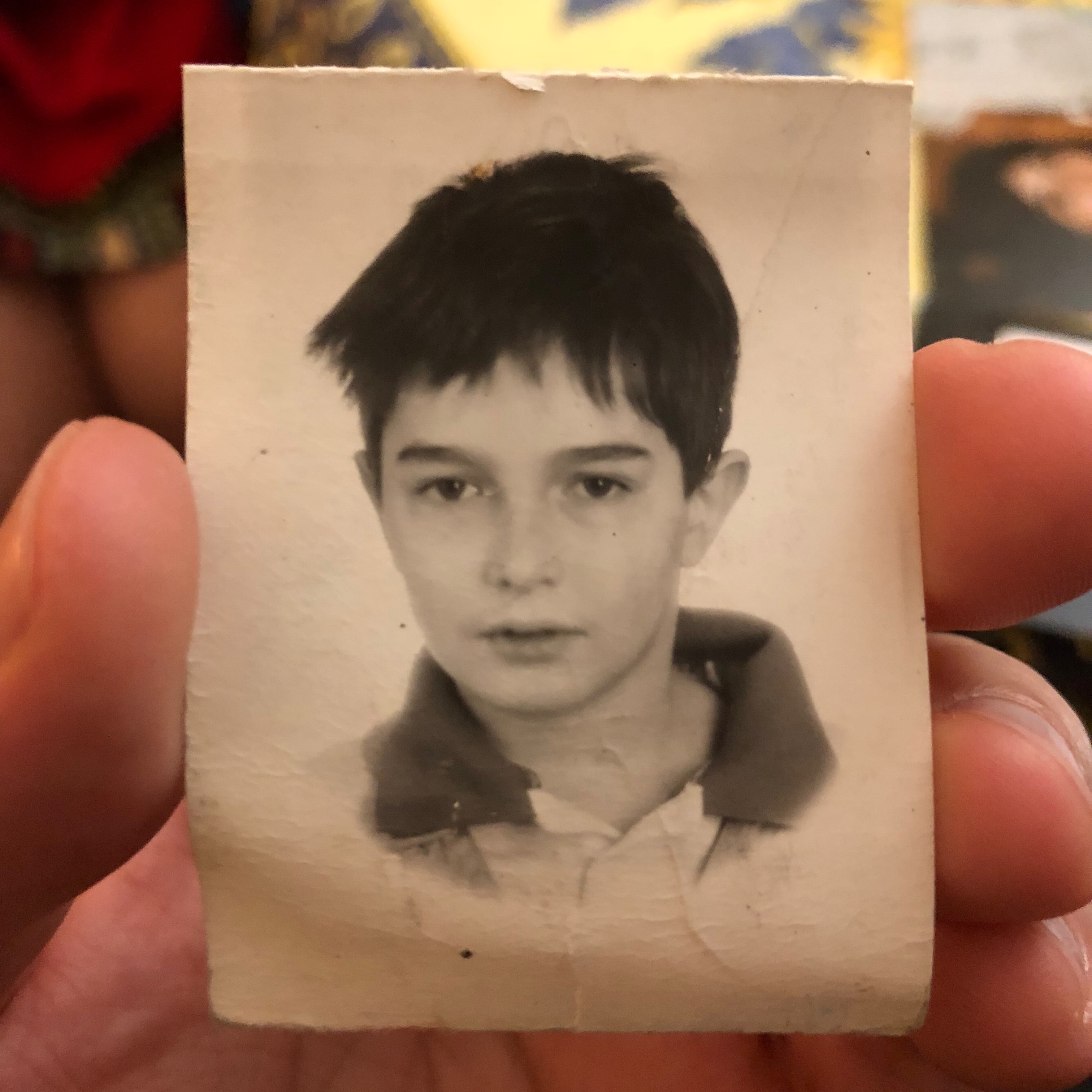A photo of a black and white passport-sized childhood photograph of the author