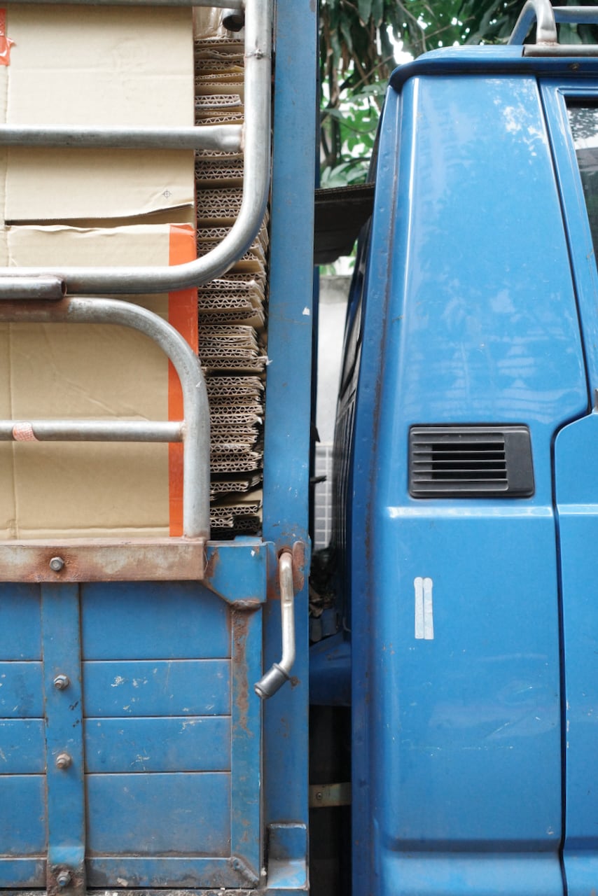 Detail of the cab of a clasic blue Delica truck loaded with cardboard