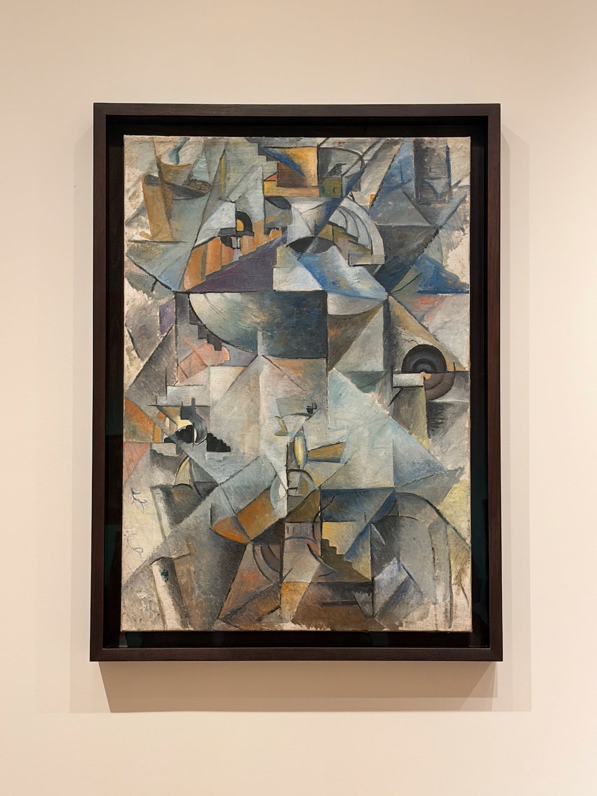 A photograph of a cubist painting in a dark wooden frame: fragmented grey, blue, ochre and white planes, with the rounded shape of a samovar and its spout discernible in the centre