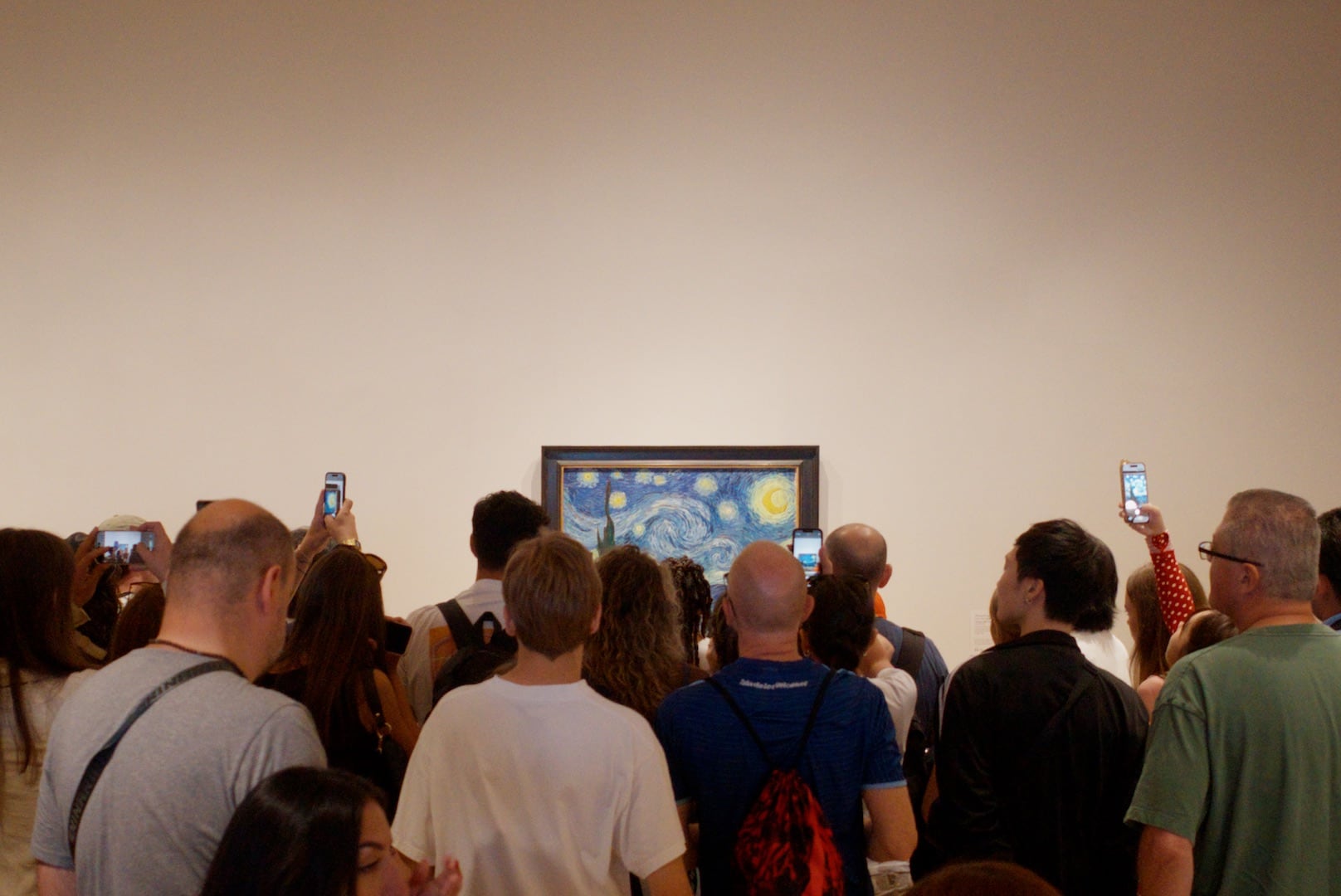 A photograph of a crowd of people in front of Van Gogh's 'Starry Night' at the Museum of Modern Art in New York City 