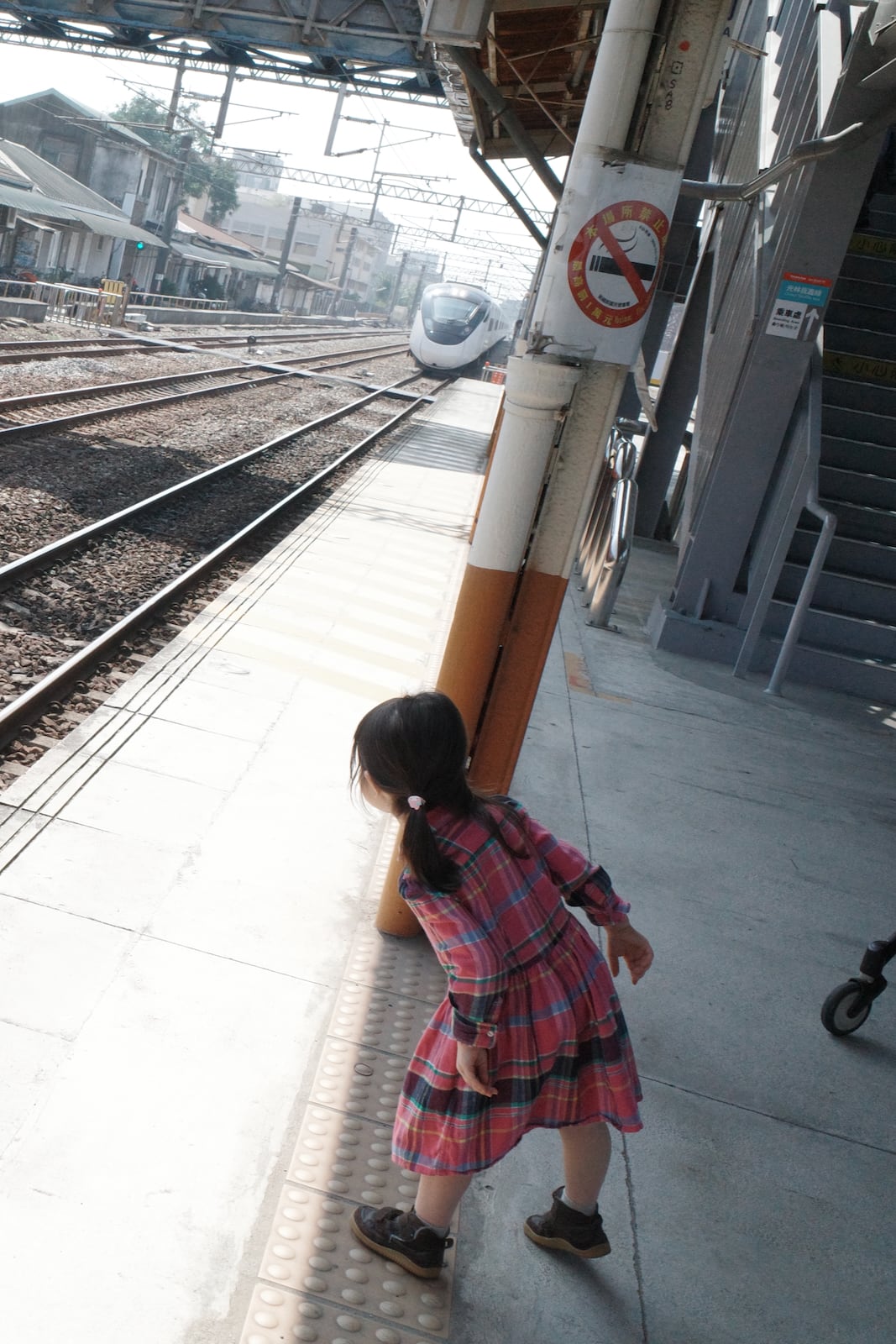 A young girl taking a look at an approaching train at the Chiayi train station