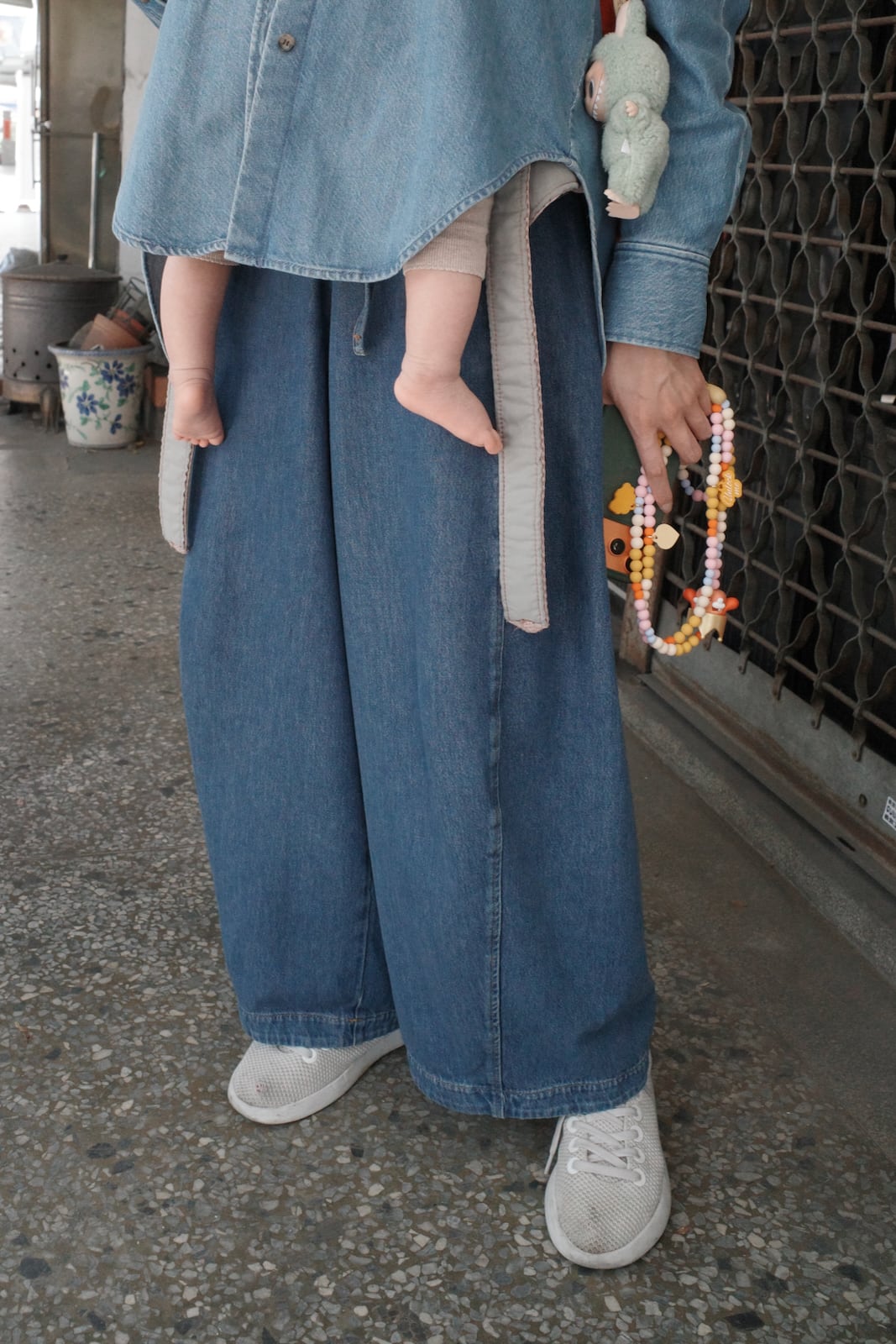 A baby's feet poking out from under his mother's overshirt