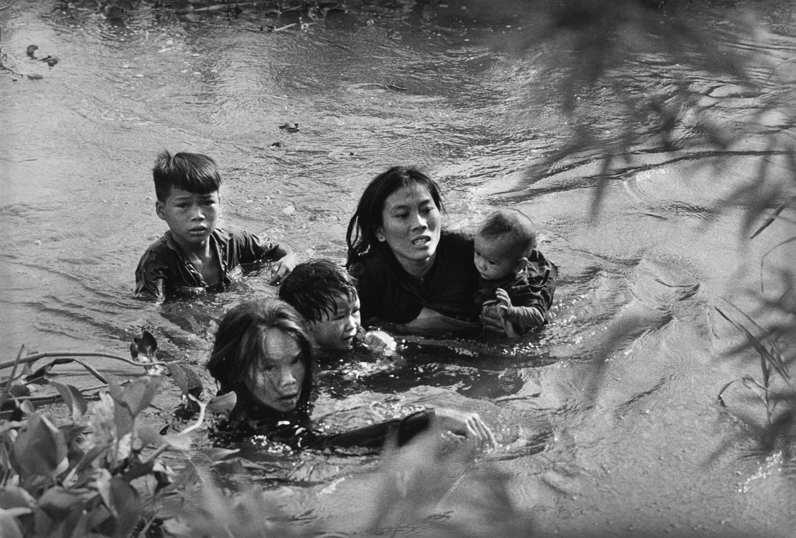 Fig. 1: “A mother and her children wade across a river to escape US bombing”, 1965. © Sawada Kyōichi