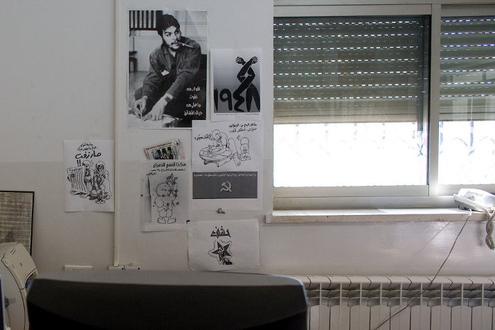 Office wall with a Che Guevara poster, a 1948 poster, and communist and Palestinian flyers next to a shuttered window